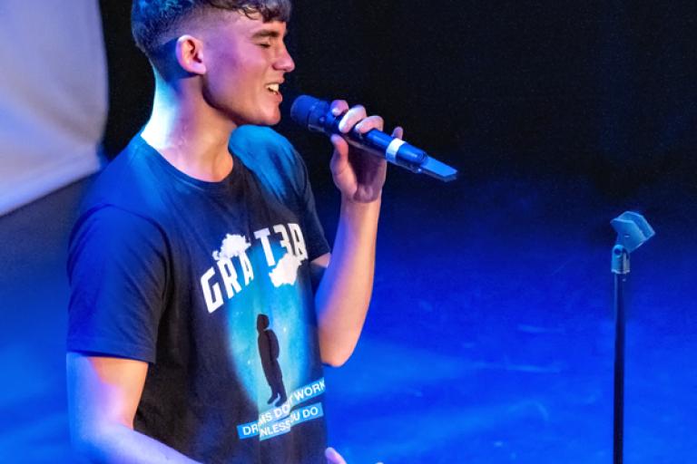 young person on stage speaking into a microphone