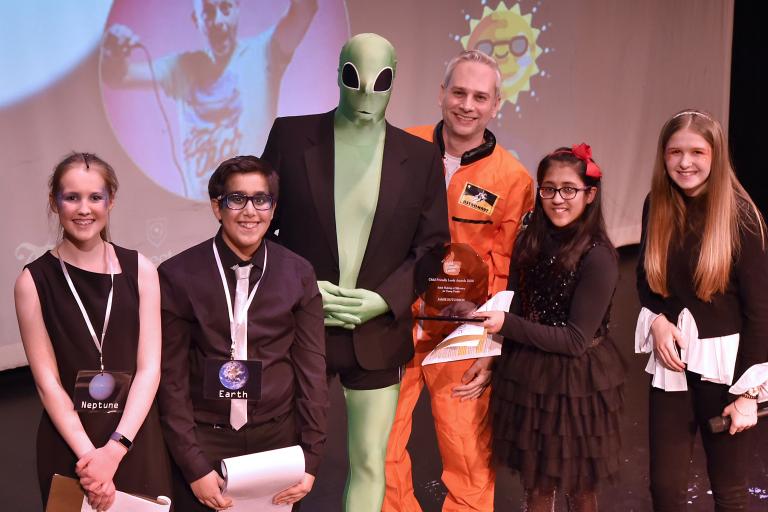 Several people posing at an awards show. One is dressed as an alien.