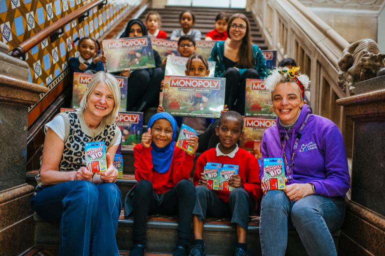 School children with the CFL team, LeedsBID staff and Leeds Children's Hospital staff, with lots of Monopoly games surrounding them.