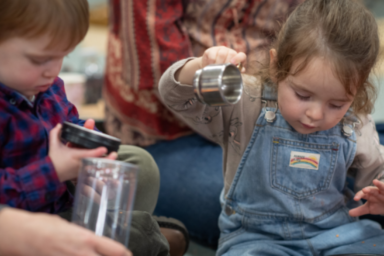 Two toddlers playing with jugs