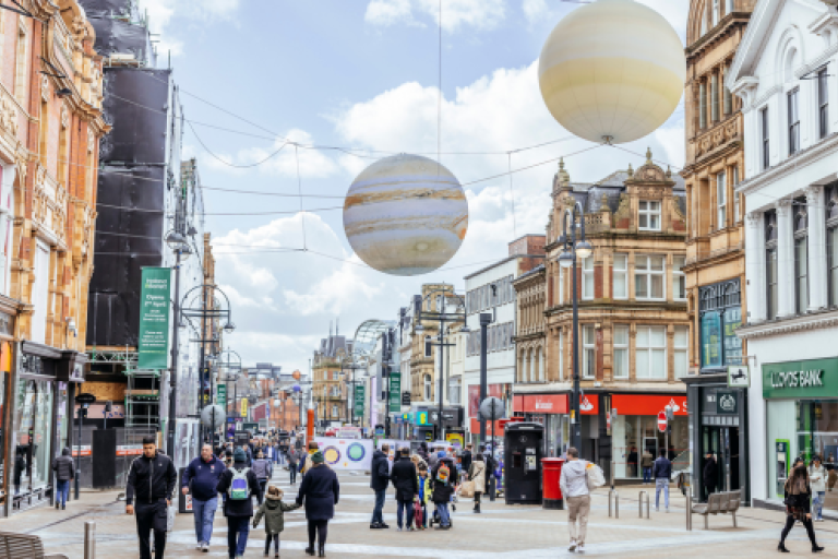 Giant planets over a busy city centre walkway