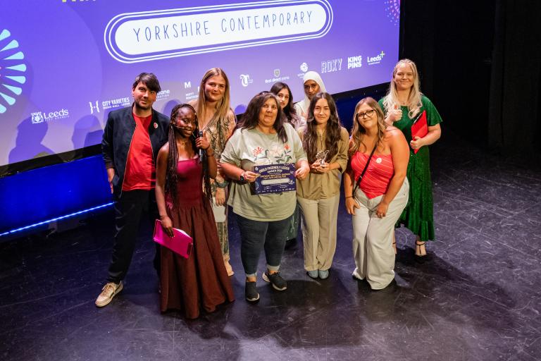 Representatives from Yorkshire Contemporary pose on stage with a certificate and award during a youth awards ceremony.