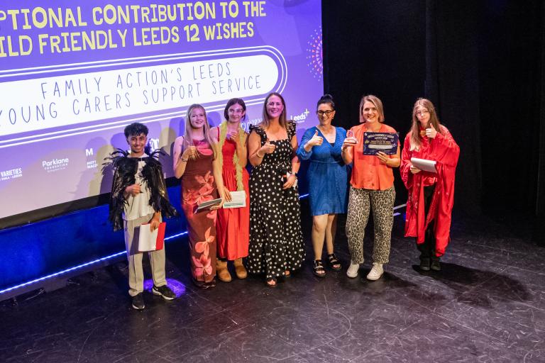 Representatives from Family Action's Leeds Young Carers Support Service pose on stage with an award plaque during an awards ceremony.