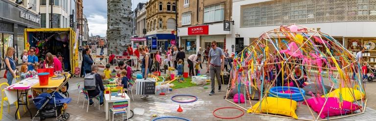 adults and children playing on climbing frames in the middle of briggate, Leeds